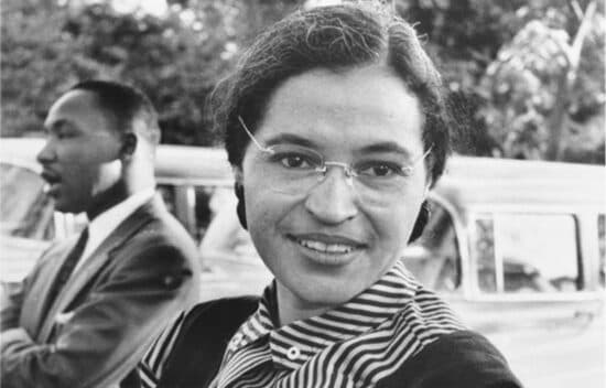 Rosa Parks sits outside. Martin Luther King Jr. sits in the background.