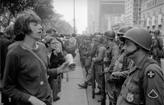 Rows of National Guard soldiers stand in the street and face protesting civilians.