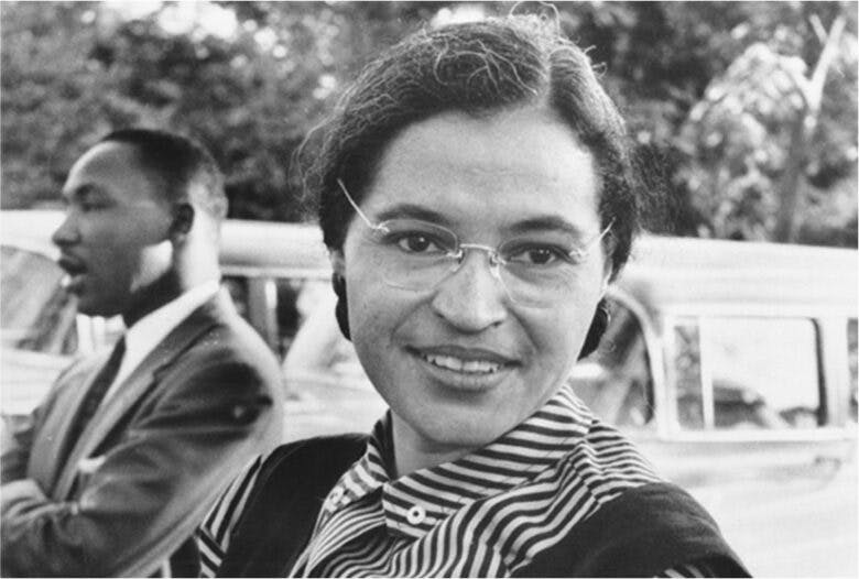 Rosa Parks sits outside. Martin Luther King Jr. sits in the background.