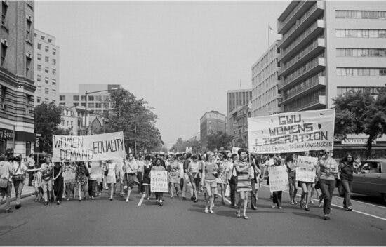 Women walk down a city street and hold signs that say Women Demand Equality and GWU Women's Liberation.