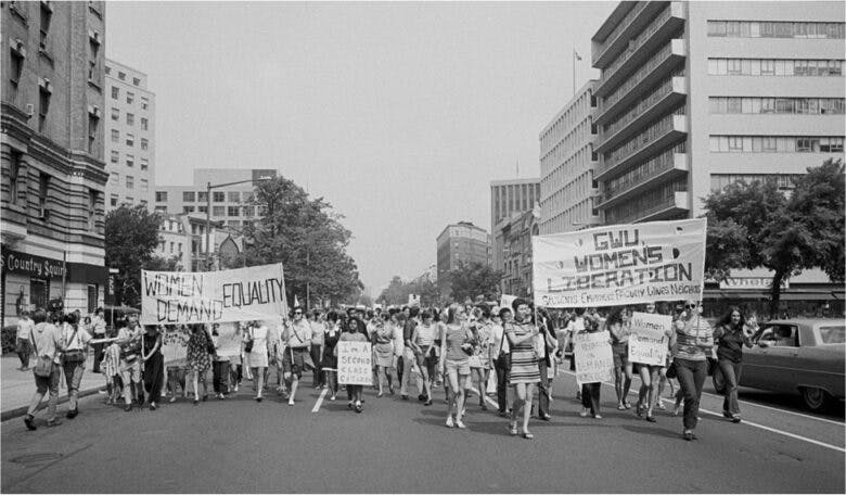 Women walk down a city street and hold signs that say Women Demand Equality and GWU Women's Liberation.