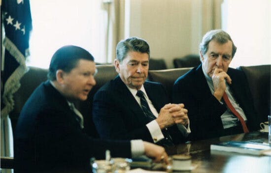 President Ronald Reagan sits at a table between Edmund Muskie and John Tower.